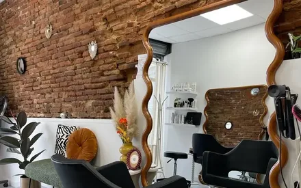 Site de Maison ChaCha Coiffure : le salon, son miroir ondulé et son mur de briques.